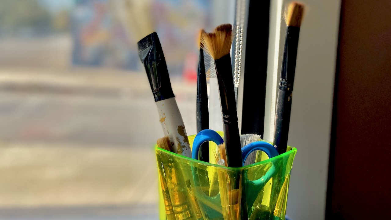 Paintbrushes in a neon green cup
