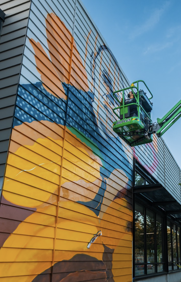 AGONZA painting a mural up on a lift